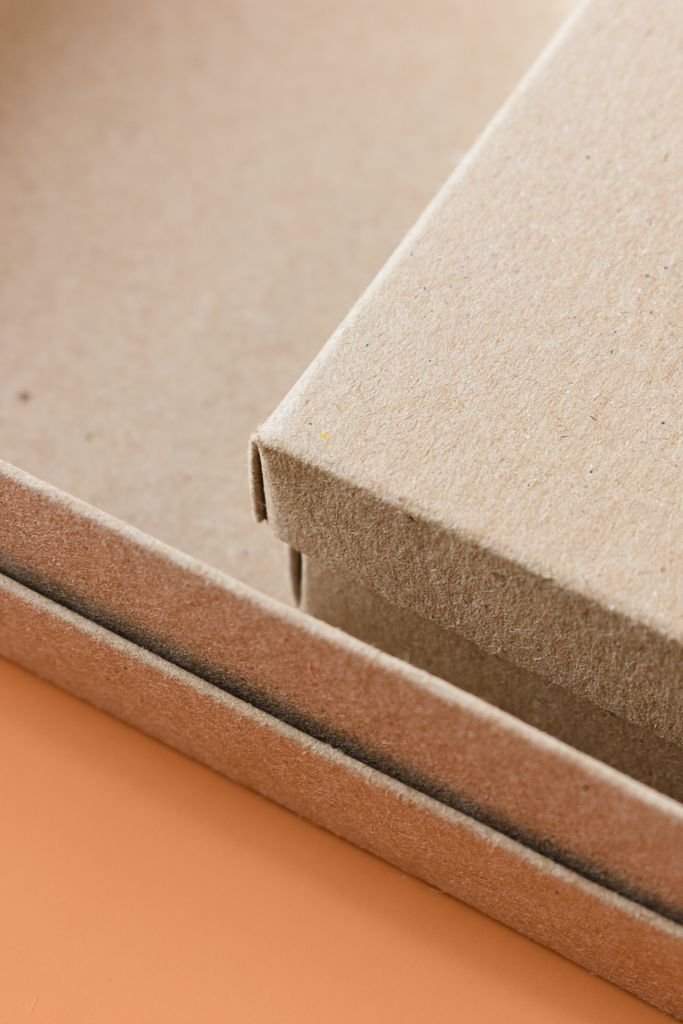 Minimalist close-up of eco-friendly cardboard packaging boxes on an orange background.